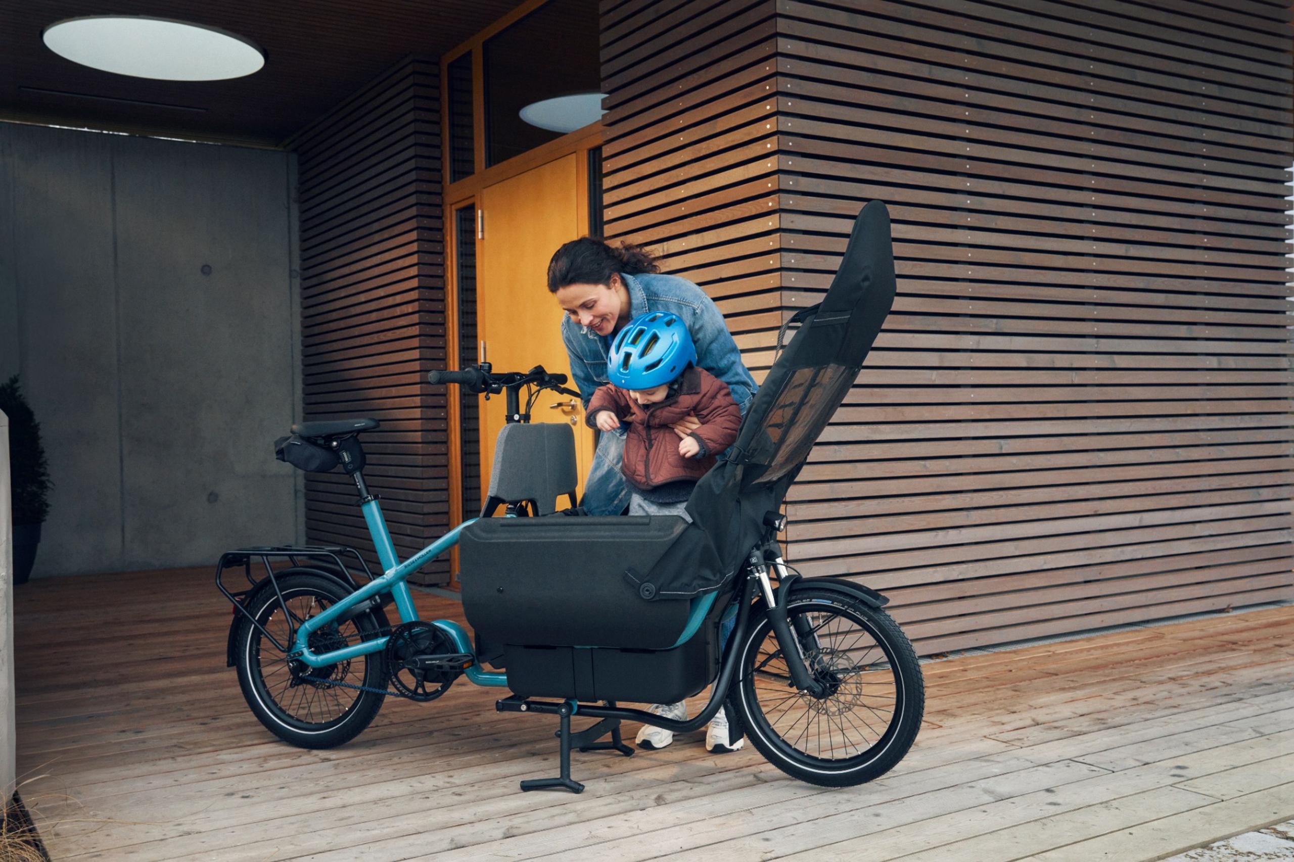 24_Zubehoer_Kinderverdeck_Carrie_RM_M_11166_02_Einsteigen_resized_2560px Slitesterkt regntrekk til Basic Box og Flex Box, beskytter lasten mot vann og smuss. Kan brukes både med åpen og lukket boks og oppbevares enkelt inni Basic Box med en festestropp